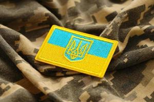 militär kamouflage tyg med ukrainska flagga på enhetlig sparre foto