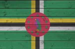 dominica flagga avbildad i ljus måla färger på gammal trä- vägg. texturerad baner på grov bakgrund foto