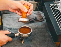 Barista Kafé framställning kaffe med manuell trycker på jord kaffe använder sig av manipulera på de trä- disken bar på de kaffe affär foto