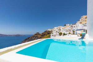 vit arkitektur på ön Santorini, Grekland. pool på lyxhotell. vacker utsikt, himmel över blått hav. sommarsemester och semester som resmål koncept, fantastisk turism bakgrund foto