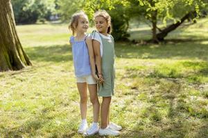 två liten flickor stående tillbaka till tillbaka i de parkera foto