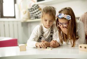två söt liten flickor spelar med förskola pedagogisk leksaker foto