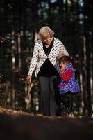 mormor och henne autistisk stor dotter njuter Semester tillsammans utomhus, liggande på grön gräs på filt och leende till kamera. fritid familj livsstil, lycka och ögonblick. foto