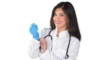 en ung kvinna läkare med stetoskop sätta en medicinsk handskar, isolerat på vit bakgrund foto
