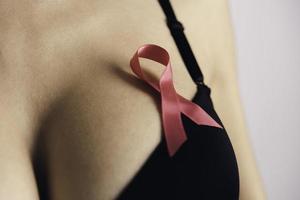 hälsa vård, medicin och bröst cancer medvetenhet begrepp. ung kvinna i behå med rosa band symbol foto