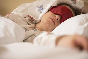 en ung kvinna sovande med en öga beläggning mask. foto