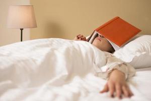 en ung kvinna sovande, beläggning henne ögon med bok foto