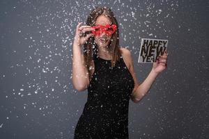 skön kvinna fira ny år med konfetti och champagne innehav tecken. isolerat foto