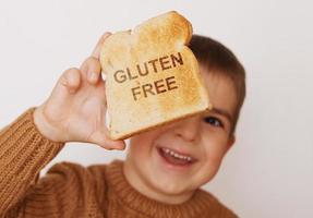 förskola pojke med rostat bröd utan gluten. friska mat. gluten intolerans förbi barn. foto