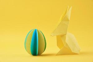 papper origami esater kanin och färgad ägg på de gul bakgrund foto