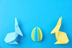 två papper origami esater kaniner och färgad ägg på bl. påsk firande foto