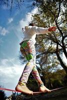 ung kvinna balansering och Hoppar på slackline. kvinna gående, Hoppar och balansering på rep foto