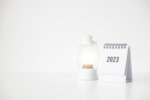 2023 företag kalender och lampa på kontor tabell i ny år dag. göra en arbete planen för de Start av de år. begrepp handla om firande, företag, jul, ny år. foto