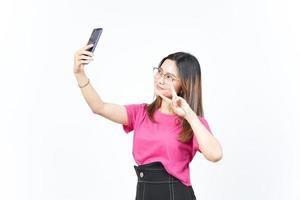 ta en selfie använder sig av smartphone av skön asiatisk kvinna isolerat på vit bakgrund foto