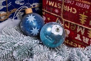 kreativ diy hantverk hobby. framställning handgjort hantverk jul ornament och bollar med känt gran träd. jul träd med färgrik bollar och gåva lådor över vit tegel vägg med blå och vit bollar foto