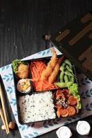 japansk bento låda med korv, guldklimp, ägg, och tempura räka foto