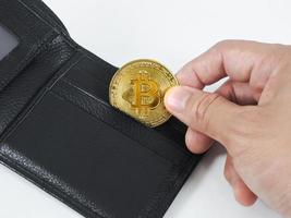 närbild hand plocka upp gyllene bitcoin på plånbok vit bakgrund foto