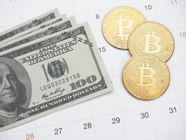pengar dollar och gyllene bitcoin på kalender schema foto