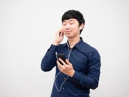 asiatisk man lyssnande musik med hörlur och håll mobiltelefon Lycklig och koppla av känsla foto