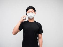 asiatisk man bär mask talande med mobil telefon på vit bakgrund foto