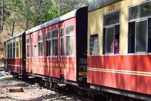 leksakståg rör sig på bergssluttningar, vacker utsikt, ena sidan berg, ena sidan dalen rör sig på järnväg till kullen, bland grön naturskog. leksakståg från kalka till shimla i indien, indiskt tåg foto