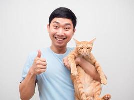 ung man innehav inhemsk härlig katt känsla Lycklig och visa tumme upp foto