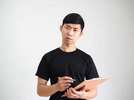 asiatisk ung man innehav trä Urklipp och silver- penna i hand allvarlig ansikte se på kamera på vit isolerad, arbete begrepp foto