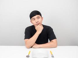 asiatisk man tänkande handla om middag på de tabell med bestick foto