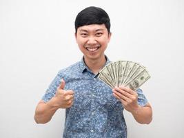 asiatisk man lycka tumme upp med en massa av pengar i hand isolerat foto