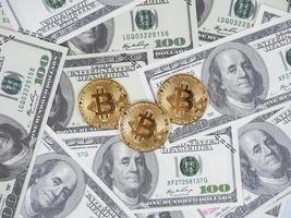 tre gyllene bitcoin på en massa av pengar räkningen dollar topp visa, digital pengar begrepp foto