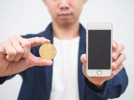 närbild man visa guld bitcoin mynt och mobil telefon i hans hand de digital pengar begrepp crypto på vit bakgrund foto