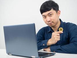 man Sammanträde med bärbar dator gest självsäker visa bitcoin i hand foto