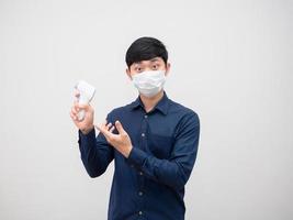 asiatisk man bär mask föreslå infraröd temometer i hans hand för skanna porträtt vit bakgrund foto