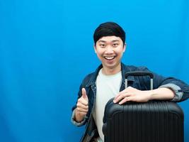 asiatisk man leende med bagage tumme upp leende blå bakgrund foto