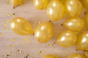 gyllene ballonger och konfetti på en trä- golv. förberedelse för en födelsedag eller Övrig fest foto