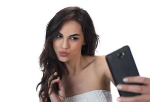 bild av skön brunett kvinna skrattande medan tar selfie Foto på mobiltelefon isolerat över vit bakgrund
