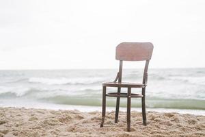 årgång trä- stol på de sand förbi de hav i en storm foto