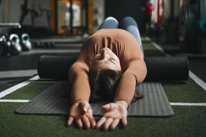 ung brunett kvinna håller på med stretching pilates på massage rulla i kondition klubb Gym foto