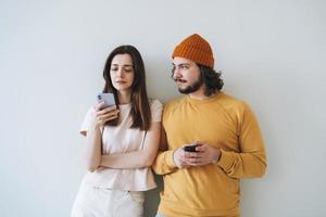 par ung familj hipsters använder sig av mobil telefoner på grå vägg bakgrund foto