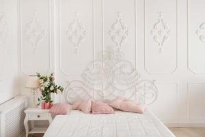 vacker ljus sovrumsinredning. sovrum med stor säng. säng med rosa kuddar foto