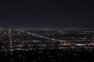 Drönare skott av upplyst modern stadsbild med mörk himmel i bakgrund på natt foto