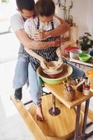 med henne pojkvän eller Make. ung kvinna keramiker inomhus med handgjort lera produkt. uppfattning av krukmakeri foto