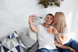 man innehav telefon och framställning selfie av han själv och hans flickvän foto
