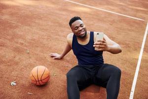 framställning selfie. afrikansk amerikan man spelar basketboll på de domstol utomhus foto