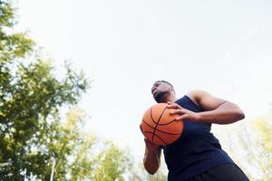 molnig väder. afrikansk amerikan man spelar basketboll på de domstol utomhus foto