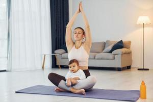 håller på med yoga övningar. mor med henne liten dotter är på Hem tillsammans foto