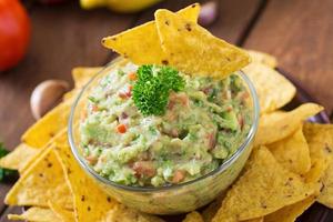 guacamole avokado, lime, tomat, lök och koriander, serveras med nachos - traditionellt mexikanskt mellanmål foto