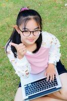 härlig flicka med en bärbar dator på de gräs foto