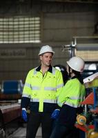 ung kvinna ingenjör inlärning till springa maskineri på en fabrik med veteran- ingenjörer foto