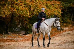 en skolålder pojke rider en häst i de dovbush sten parkera i ukraina. foto